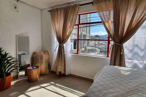 a bedroom with a bed and a large window at A su Merced entre Nubes, Montañas y Café. in La Merced