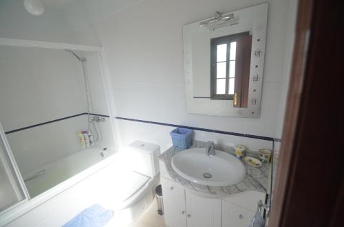 a white bathroom with a sink and a mirror at The Occidental House in Tamaduste