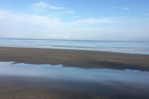a beach with a reflection of the ocean in the water at Vacaciones Playa Club Casa Blanca Same Esmeraldas in Same