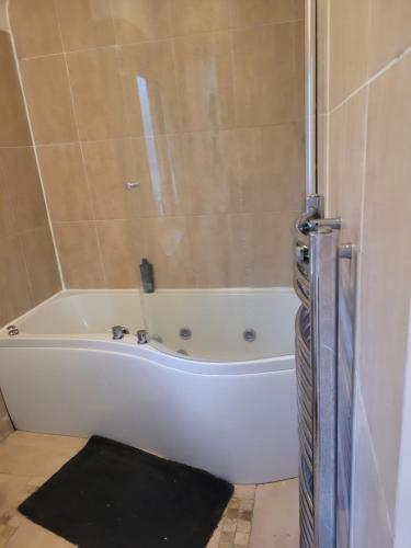 a white bath tub in a bathroom with a black rug at No 5 Decent Homes ( Luxury Extra-large bedroom) in Ashton under Lyne