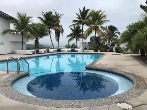 uma grande piscina com palmeiras ao fundo em Vacaciones Playa Club Casa Blanca Same Esmeraldas em Same
