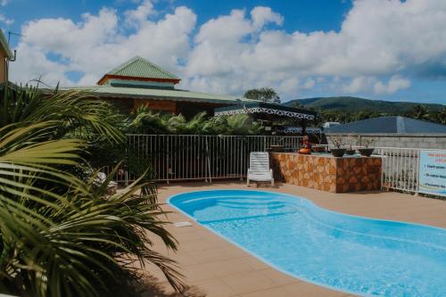a swimming pool in front of a house at Résidence Le Palmier Royal in Sainte-Rose