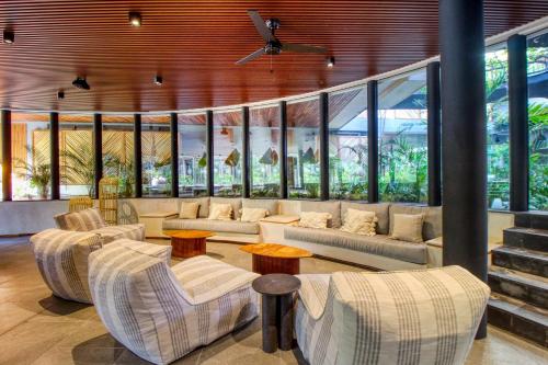 a living room with couches and tables and windows at Miraluna 233 at Luum Zama in Tulum