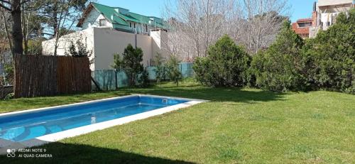 un patio trasero con una piscina en el césped en Chalet de 2 dorm- 1baño - Piscina en Valeria del Mar