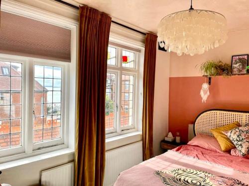 a bedroom with a bed and windows and a chandelier at 3 Bedroom Spacious Seaside Apartment with Estuary Views in Southend-on-Sea