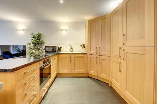 a large kitchen with wooden cabinets and a sink at City Centre, 2 Bedroom, Secured Parking, 3 King Bed, WiFi Sleep 6 Guest Comfortable on Three King Size Beds, Jewellery Quarter , Birmingham City Centre , Allocated Secured Parking in Birmingham