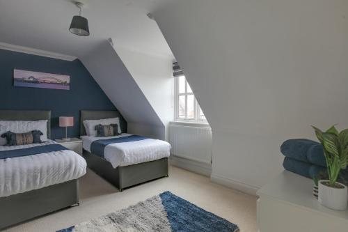 um quarto com 2 camas e uma parede azul em Elizabeth Townhouse Braintree 