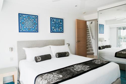 a white bedroom with two beds and a mirror at Netanya Noosa Beachfront Resort in Noosa Heads