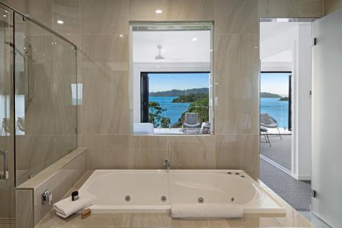 a bath tub in a bathroom with a view of the water at Hidden Cove on Hamilton Island by HIHA in Hamilton Island