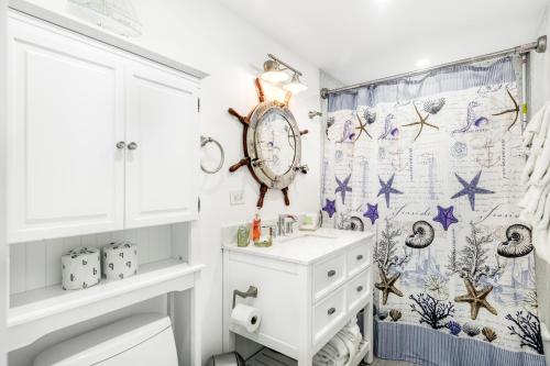 a bathroom with a sink and a clock on the wall at A Wave From it All in Key Colony Beach