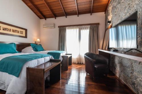 um quarto de hotel com duas camas e uma televisão em Bemar Carmelo Hotel em Carmelo