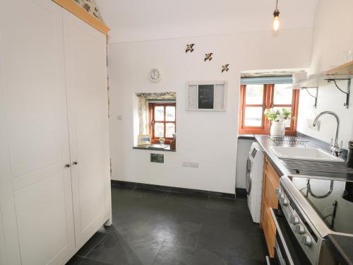 a kitchen with white cabinets and a black floor at Nyth Y Wennol in Holyhead