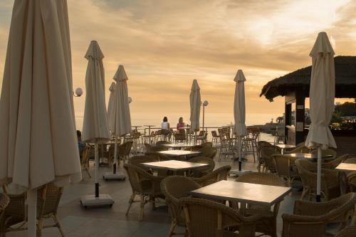 a restaurant with tables and white umbrellas on the beach at Toboso Apar - Turis in Nerja