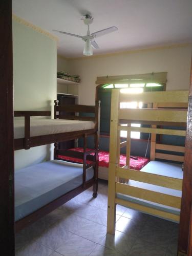 a room with three bunk beds and a ceiling at Casa linda e confortável a 3 min da praia!!! in Peruíbe