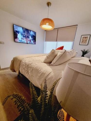 a bedroom with a bed with a tv on the wall at Departamento nuevo en sector costa de montemar in Concón