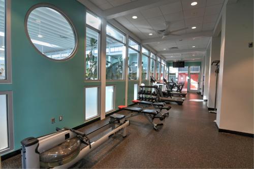 a gym with a row of treadmills and a mirror at Oasis Hotel and Conv Center, an Ascend Collection Hotel in Springfield