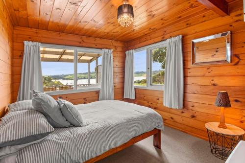 1 dormitorio con 1 cama y 2 ventanas en Bay Vista Views - Raglan Holiday Home, en Raglan