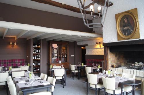 a restaurant with tables and chairs and a fireplace at Logis La Ferme Du Vert in Wierre-Effroy