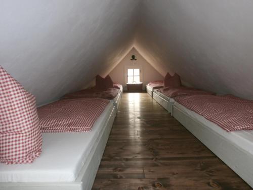 a row of beds in a attic with a window at Penzion Roubenka in Hukvaldy