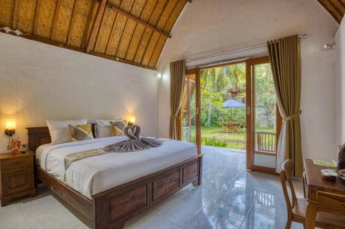 una camera con letto e porta di accesso a un giardino di Maharga Bungalows a Nusa Penida