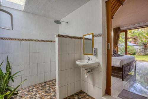 un bagno con lavandino, specchio e letto di Maharga Bungalows a Nusa Penida