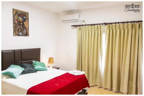 a bedroom with a bed with a red blanket and a window at Hotel Tuunteytas in Villamontes