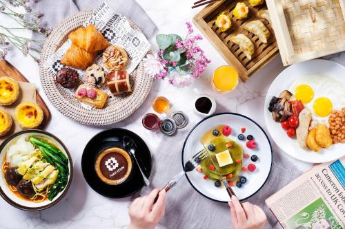 a table with plates of food and a person holding chopsticks at Hotel ICON in Hong Kong