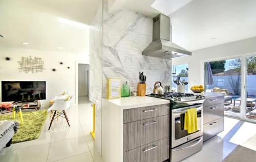 a kitchen with a stove top oven next to a living room at Amarillo House - Luxury Home with Pool & Spa in Palm Springs