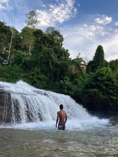 a man standing in the water in front of a waterfall at Nisha homestay inn in Peradeniya
