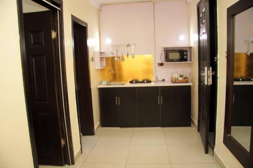 Posh Hotel and Suites Victoria Island في لاغوس: مطبخ مع دواليب سوداء وارضية بلاط بيضاء