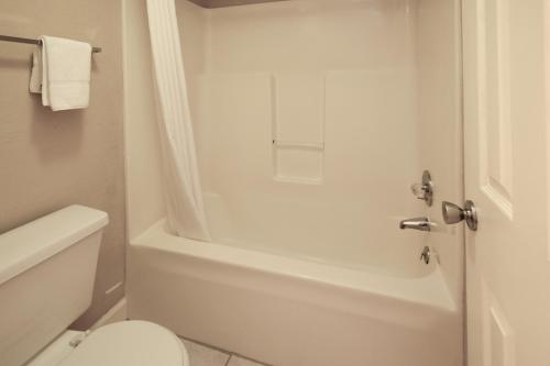 Mountain Aire Inn Sevierville - Pigeon Forge في سيفيرفيل: حمام مع حوض استحمام أبيض ومرحاض