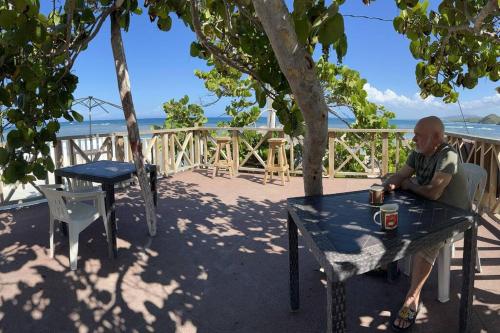 un hombre sentado en una mesa con un trago encima en Friendly Kite School, hotel and bar, en Villa Vásquez