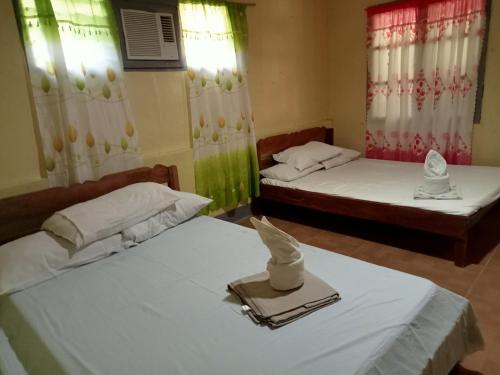 a room with two beds with towels on them at Basio's Place Tourist Inn by RedDoorz in San Vicente