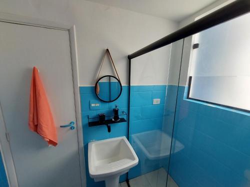 Baño azul con lavabo y espejo en Sala living na Av da Praia., en Santos