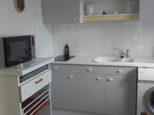 une cuisine blanche avec un évier et un micro-ondes dans l'établissement Studio calme à Arcachon - Terrasse - Proche plage et centre - Équipé pour 2 pers. - FR-1-319-42, à Arcachon