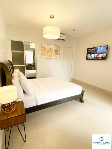 a bedroom with a bed and a tv on the wall at HARMAN SUITES Moalboal in Moalboal