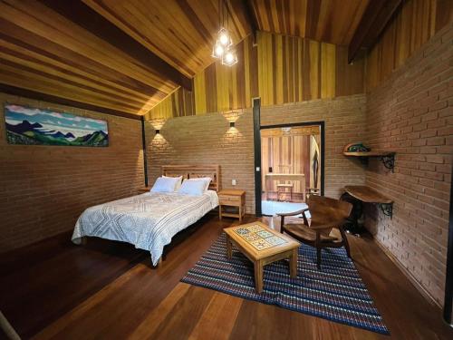 a bedroom with a bed and a table in a room at Chalés Das Estrelas in Visconde De Maua