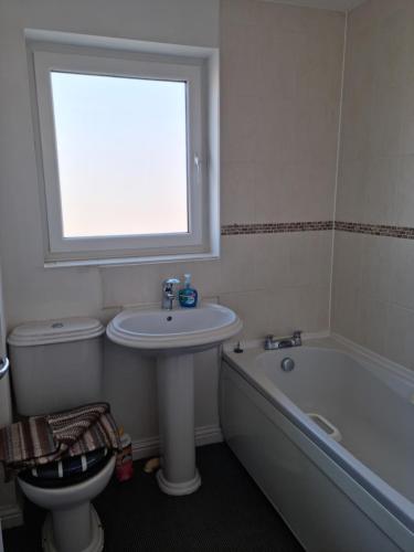 a bathroom with a sink and a toilet and a window at Driftmark Aberavon Beach The Crownlands 4 bedrooms Large Driveway parking 2 mins from Beach in Port Talbot