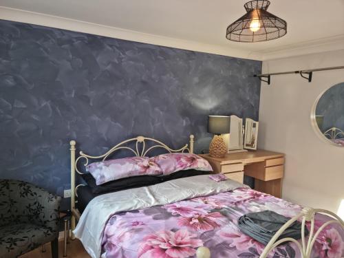a bedroom with a bed and a blue wall at Driftmark Aberavon Beach The Crownlands 4 bedrooms Large Driveway parking 2 mins from Beach in Port Talbot