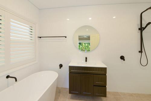 a bathroom with a tub and a sink and a mirror at The Acreage Boutique Guesthouse in North Avoca