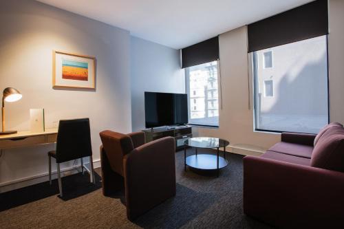 a living room with a couch and a tv at CitiClub Hotel Melbourne in Melbourne