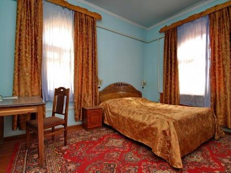 1 dormitorio con 1 cama, escritorio y ventanas en Islambek Khiva, en Khiva