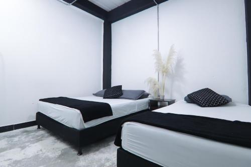 two beds in a room with white walls at Hotel Casa Malibú in Medellín