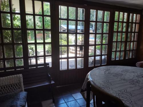 Habitación con ventanas grandes, mesa y banco. en Hermosa Casa Pileta Exclusiva Zona Residencial Gastronómica Parque de la ciudad de San Rafael en San Rafael