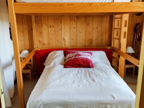 - un lit avec un oreiller rouge dans une chambre en bois dans l'établissement Appartement cosy 2P 40m² - 6 pers - Pied des pistes avec balcons et toutes commodités - FR-1-689-113, à Villard-de-Lans