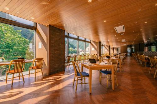 a dining room with tables and chairs and windows at Grand Blissen Hotel Jozankei in Jozankei
