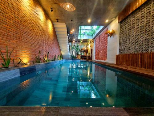 a swimming pool in a building with a brick wall at Hoi An Ti Hon House in Hoi An