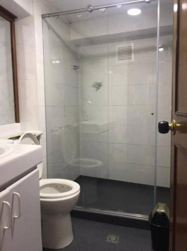 a bathroom with a toilet and a glass shower at Apartamento Manizales, excelente ubicación sector estadio in Manizales