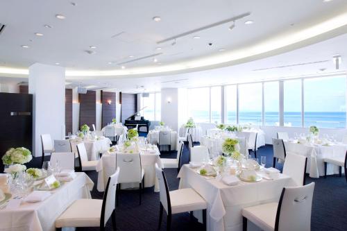 una sala da pranzo con tavoli e sedie bianchi e finestre di Hotel Aomori ad Aomori