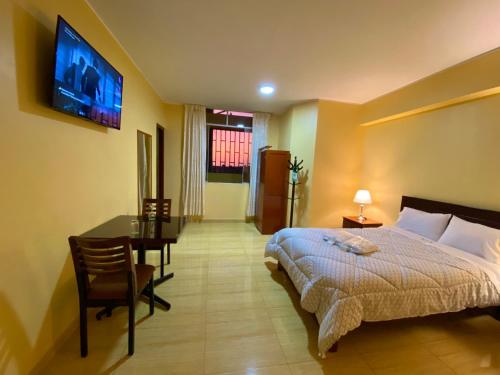 a bedroom with a bed and a desk and a tv at Hotel Las Palmeras in Huacho